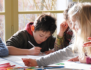 Ecolier écrivant en classe avec d'autres enfants, photographe enfant